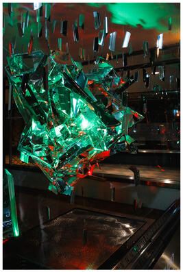 A photograph of a reflective light installation, lit in red and green.